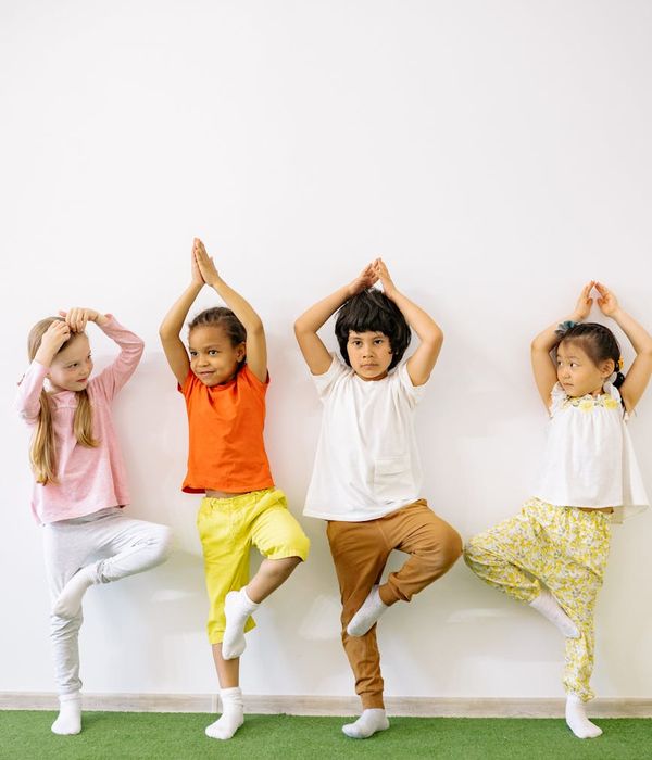 Happy child doing a simple yoga pose in a bright room.